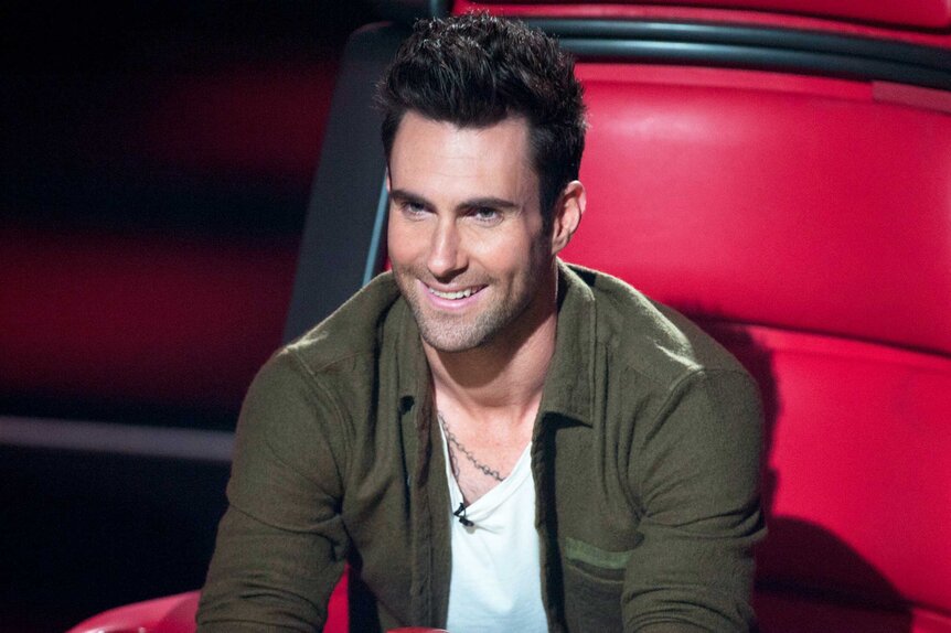 Adam Levine sits in his coaches chair with a green jacket on The Voice Season 2,