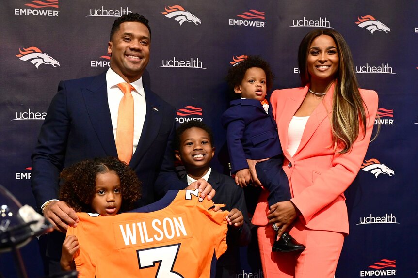 Russell Wilson holding his jersey alongside Sienna Princess Wilson, Future Zahir Wilburn, Win Harrison, and Ciara.