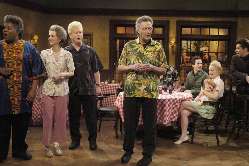 Christopher Walken and the cast of SNL sit in a restaurant on SNL Episode 3309.