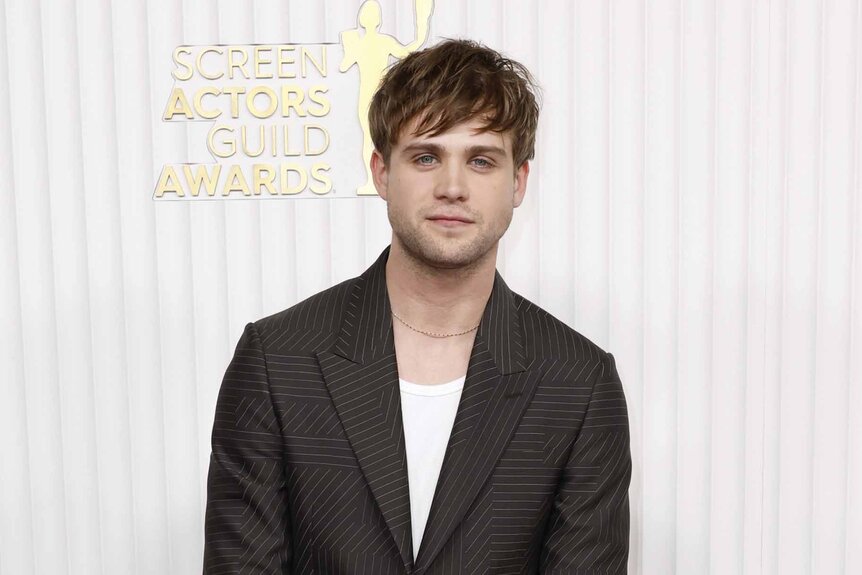 Leo Woodall smiles in a shirt and blazer.