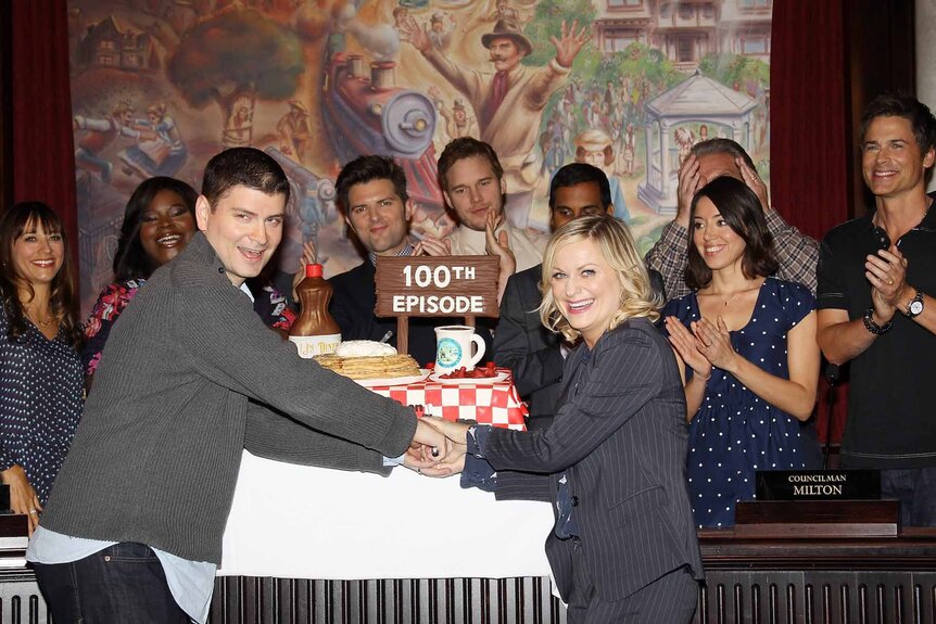 Michael Schur, Amy Poehler, and the cast of "Parks And Recreation" cut their 100th episode cake.