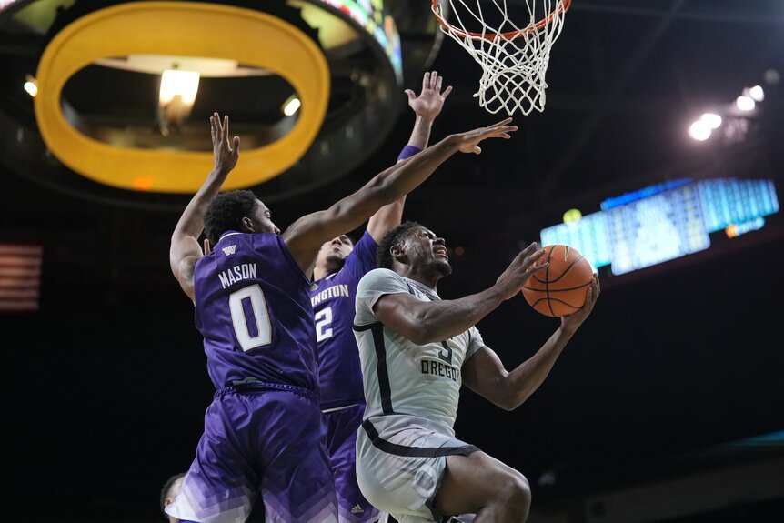 TJ Bamba #5 of the Oregon Ducks drives to the basket past Mekhi Mason #0 of the Washington Huskies during a game.