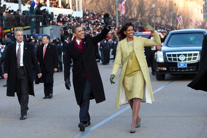 U.S. President Barack Obama and first lady Michelle Obama walk and wave during an inaugural parade.