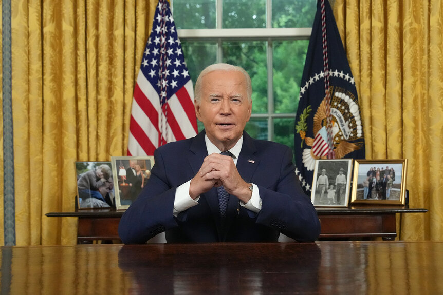 Joe Biden sits at his desk in the oval office addressing the nation