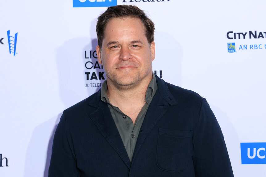 Kyle Bornheimer smiles on the red carpet in a black jacket