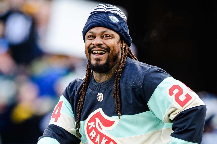 Marshawn Lynch smiling at the Pittsburgh Steelers football game.