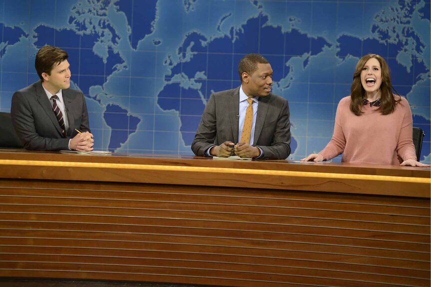 Colin Jost, Michael Che, and Vanessa Bayer sit at the Weekend Update on SNL 1666.