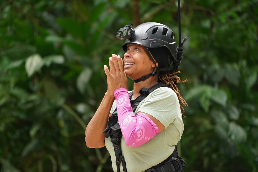 La Shell Wooten prays with a helmet on her head on Deal or No Deal Island Episode 205.