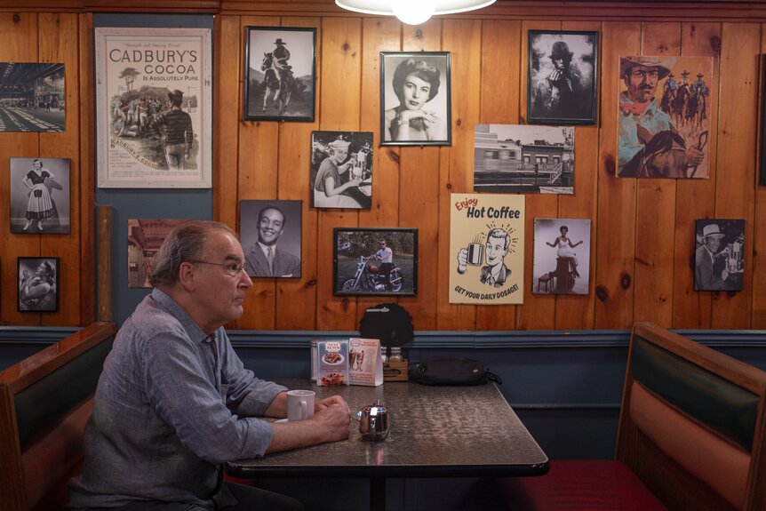 A doctor (Mandy Patinkin) sits in a diner booth on Brilliant Minds Episode 113.