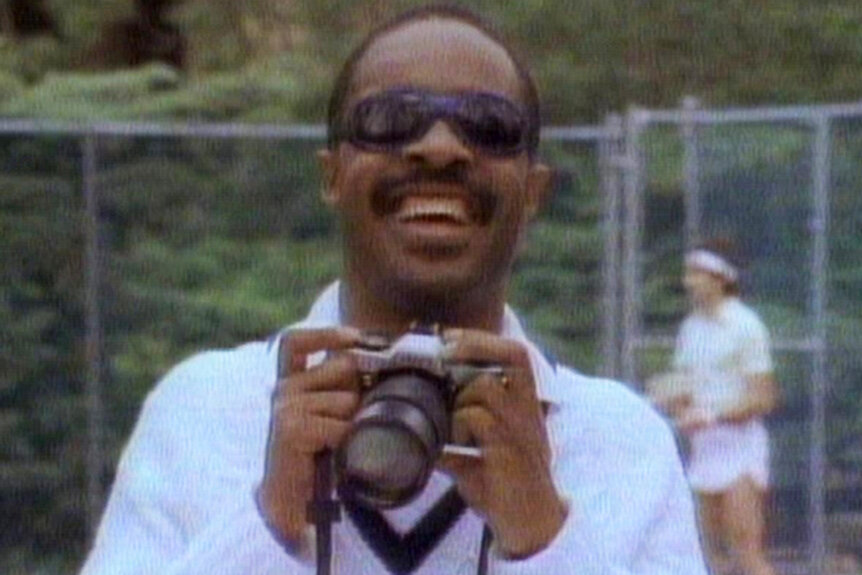 Stevie Wonder holds a camera and smiles on Saturday Night Live Season 8