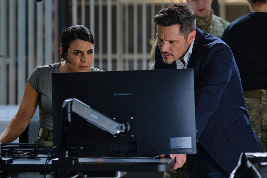 Jennifer Morales and Oliver Odell look at a computer together on The Hunting Party Season 1 Episode 2.