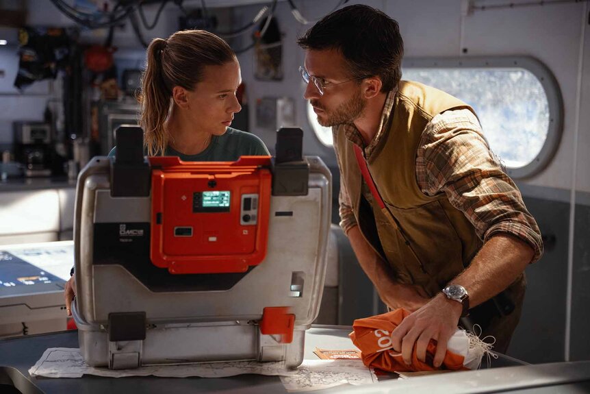 Zora Bennett (Scarlett Johansson) and Dr. Henry Loomis (Jonathan Bailey) speak next to a tech briefcase on Jurassic World Rebirth (2025).