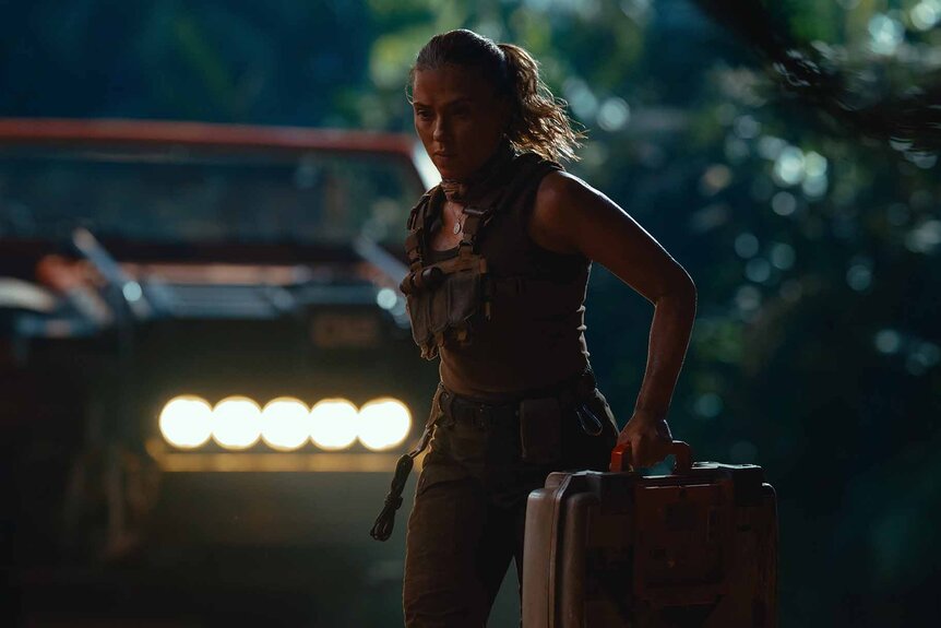 Zora Bennett (Scarlett Johansson) runs with a vest and large metal briefcase in Jurassic World Rebirth (2025).