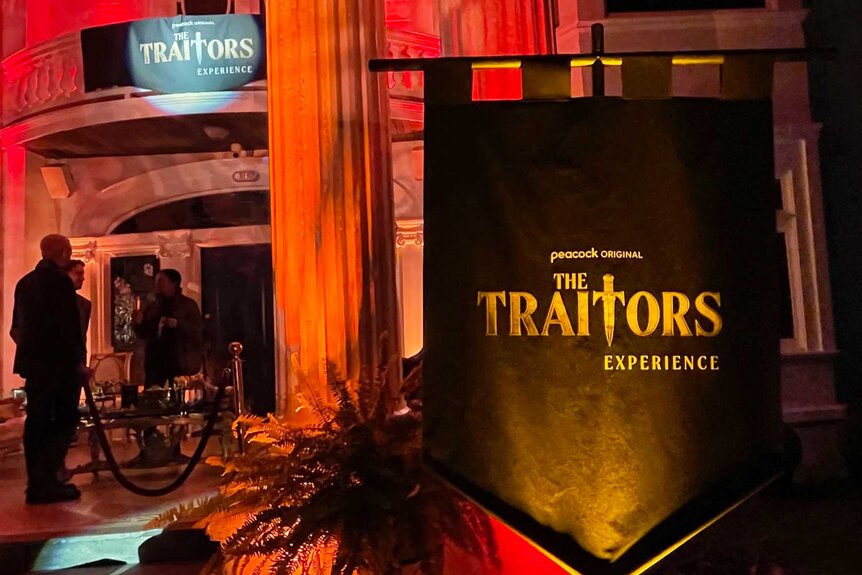 The logo for The Traitors Experience with a group of people.