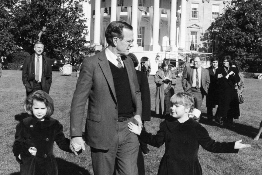 U.S. President George H. W. Bush holds hands with his granddaughters, Barbara and Jenna, in front of the White House.