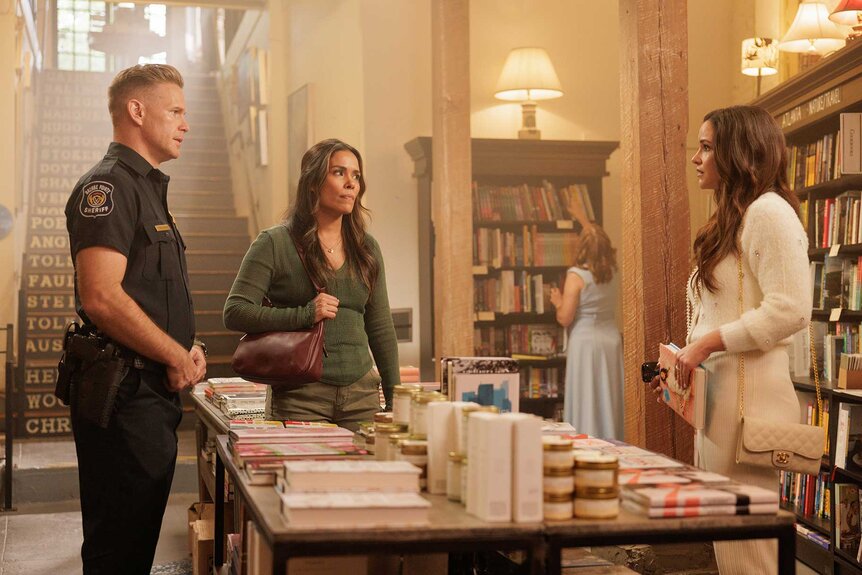 Joel, Misty, and Birdie talking in a book store in Grosse Pointe Garden Society Season 1, Episode 1.