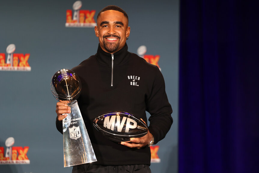 Jalen Hurts stands holding two trophies during a press conference after the 2025 super bowl