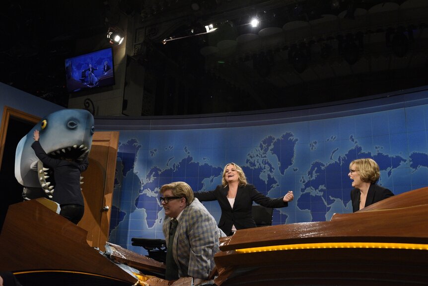 Tina Fey, Melissa McCarthy as Matt Foley, Amy Poehler, and Jane Curtin act at the Weekend Update desk on SNL40.