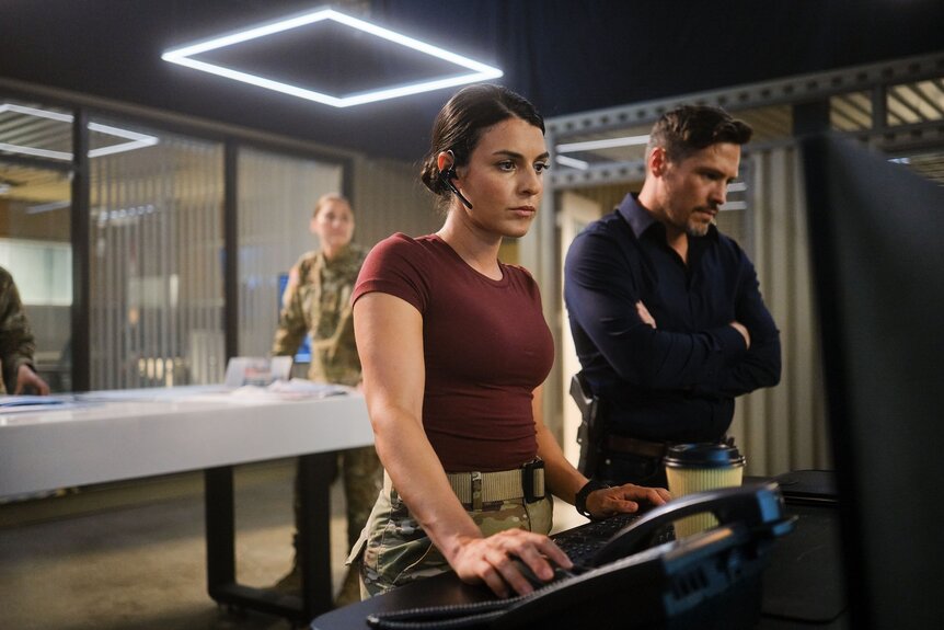 Jennifer Morales (Sara Garcia) and Oliver Odell (Nick Wechsler) work at a desk in The Hunting Party Episode 104.