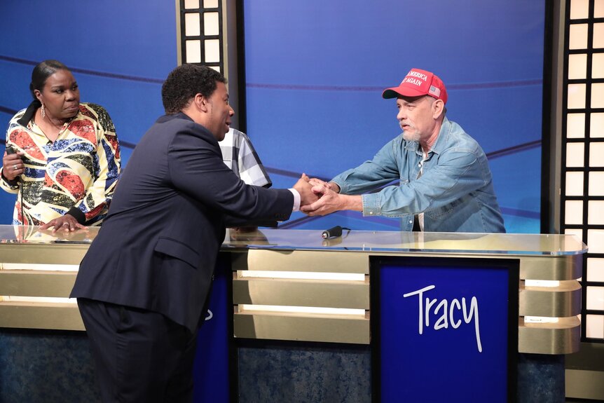 Leslie Jones Kenan Thompson and Tom Hanks standing on a game show set.