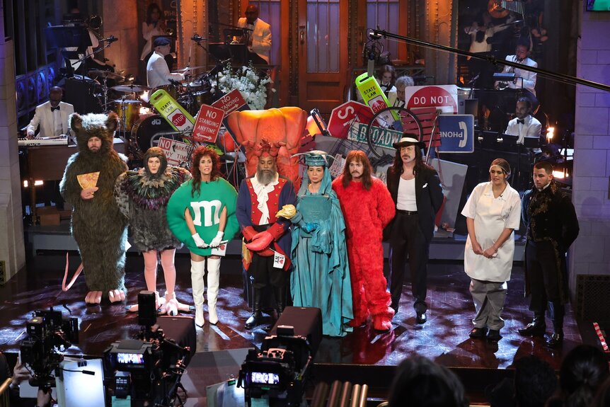 Taran Killam, Ana Gasteyer, Kristen Wiig, Kenan Thompson, Maya Rudolph, Will Forte, Jason Sudeikis, Cecily Strong, and Nick Jonas standing onstage in costumes.