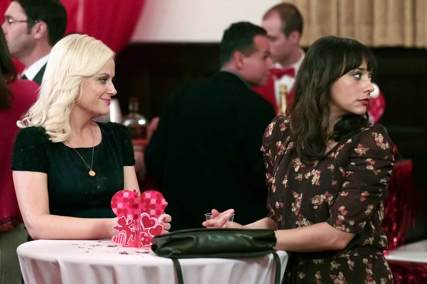 Leslie Knope and Ann Perkins sitting at a table with Valentine's decorations on Parks and Recreation Season 4, Episode 14.