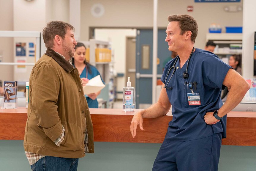 Danny and Dr. Bruce talking in a waiting room on St. Denis Medical Season 1, Episode 10.