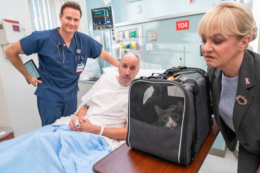 Dr. Bruce, Jonathan, and Joyce in a hospital room next to a cat on St. Denis Medical Season 1, Episode 12.