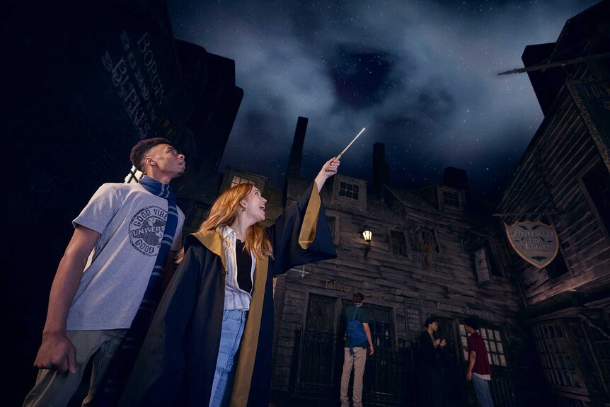 Guests holding up a wand to the sky in Universal Orlando's The Wizarding World of Harry Potter.