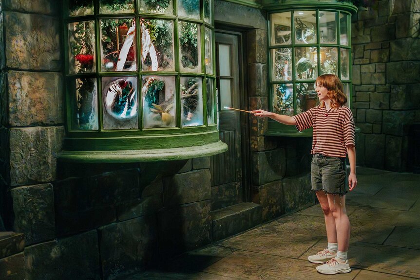 A guest holding up a wand in Universal Orlando's The Wizarding World of Harry Potter.