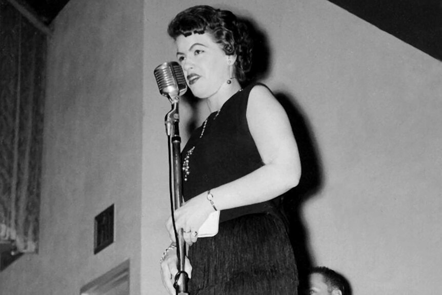 Patsy Cline standing on stage and performing.