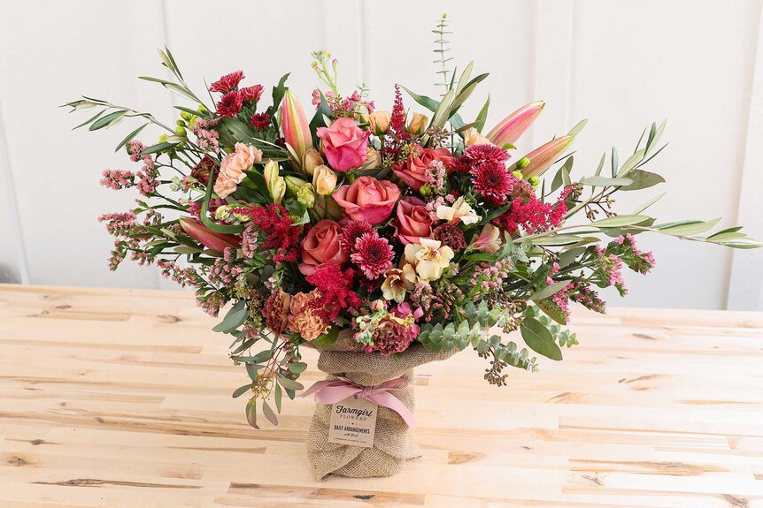 A colorful floral burlap wrapped bouquet placed on top of a table.