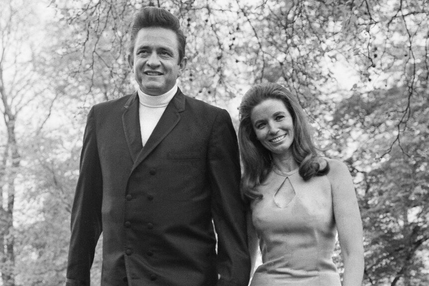 Johnny Cash and June Carter Cash hold hands together in a park