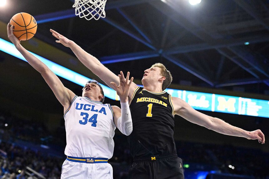 Danny Wolf of the Michigan Wolverines blocking a shot against Tyler Bilodeau of the UCLA Bruins during the NCAA Men's basketball game.