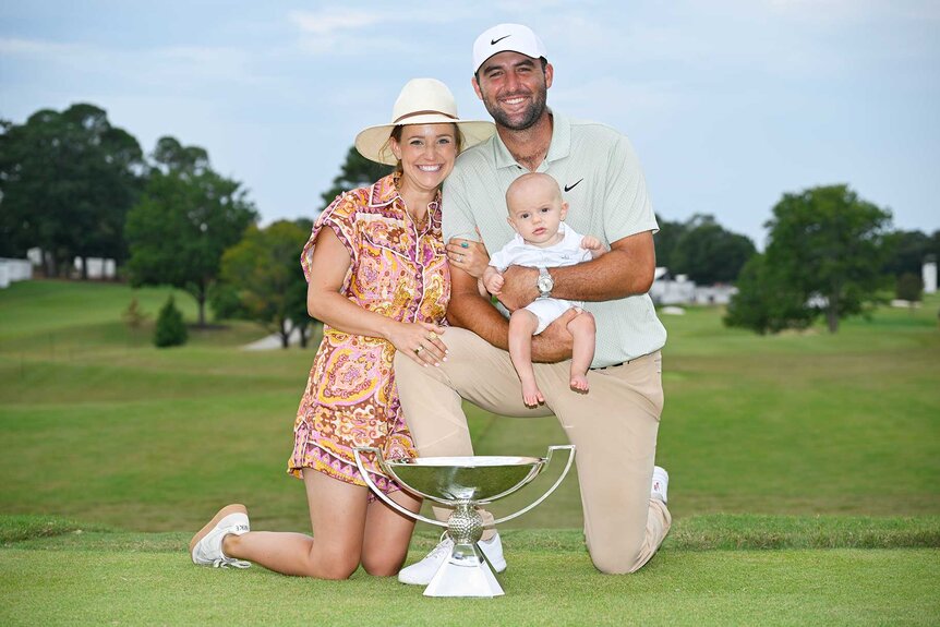 Scottie Scheffler, wife Meredith Scheffler, and son Bennett Scheffler posing with a trophy after winning the FedExCup and Tour Championship.