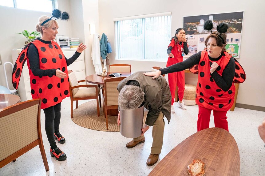 Joyce, Serena, and Alex standing around Sanderson as he throws up in a bucket in St. Denis Medical Season 1, Episode 14.