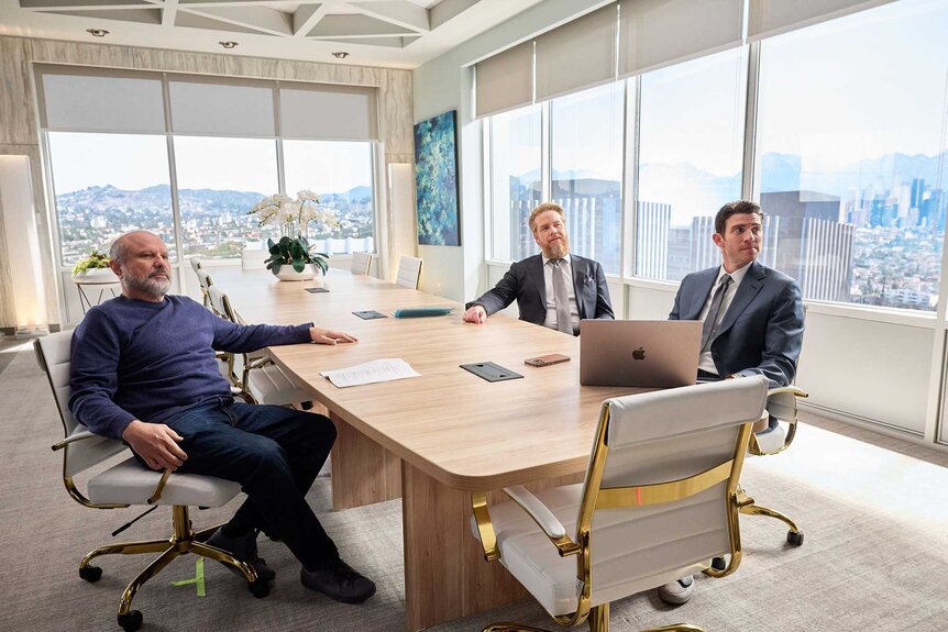 Enrico Colatoni, Stuart Lane, and Rick Dodson sitting at a table during a meeting in Suits LA Season 1, Episode 4.